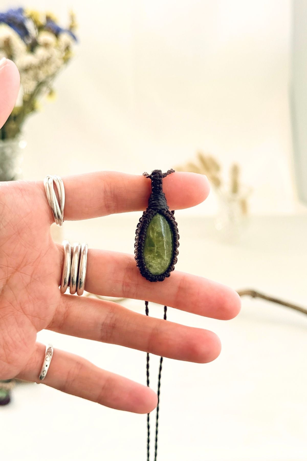 Handmade Vesuvianite macramé necklace held in hand, delicate natural gemstone jewelry