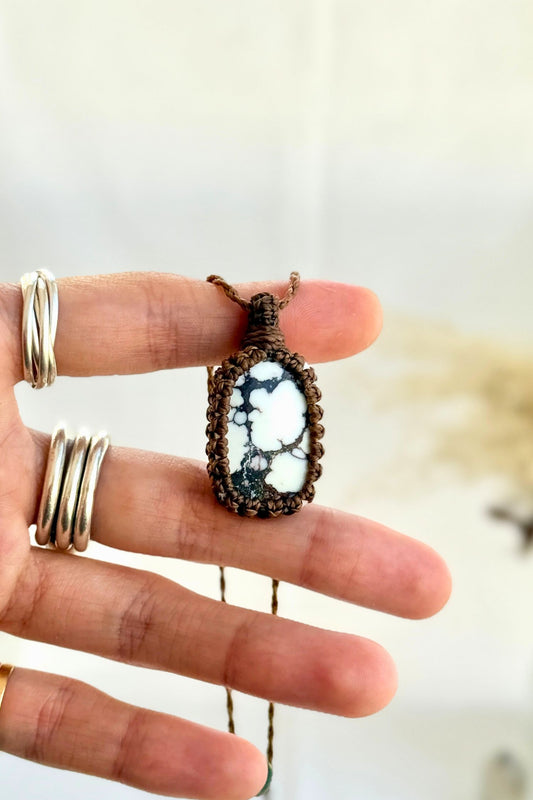 Hand holding a handmade Wild Horse Magnesite Macrame necklace from the Essence collection, featuring a high-quality gemstone in a delicate everyday-wear design.