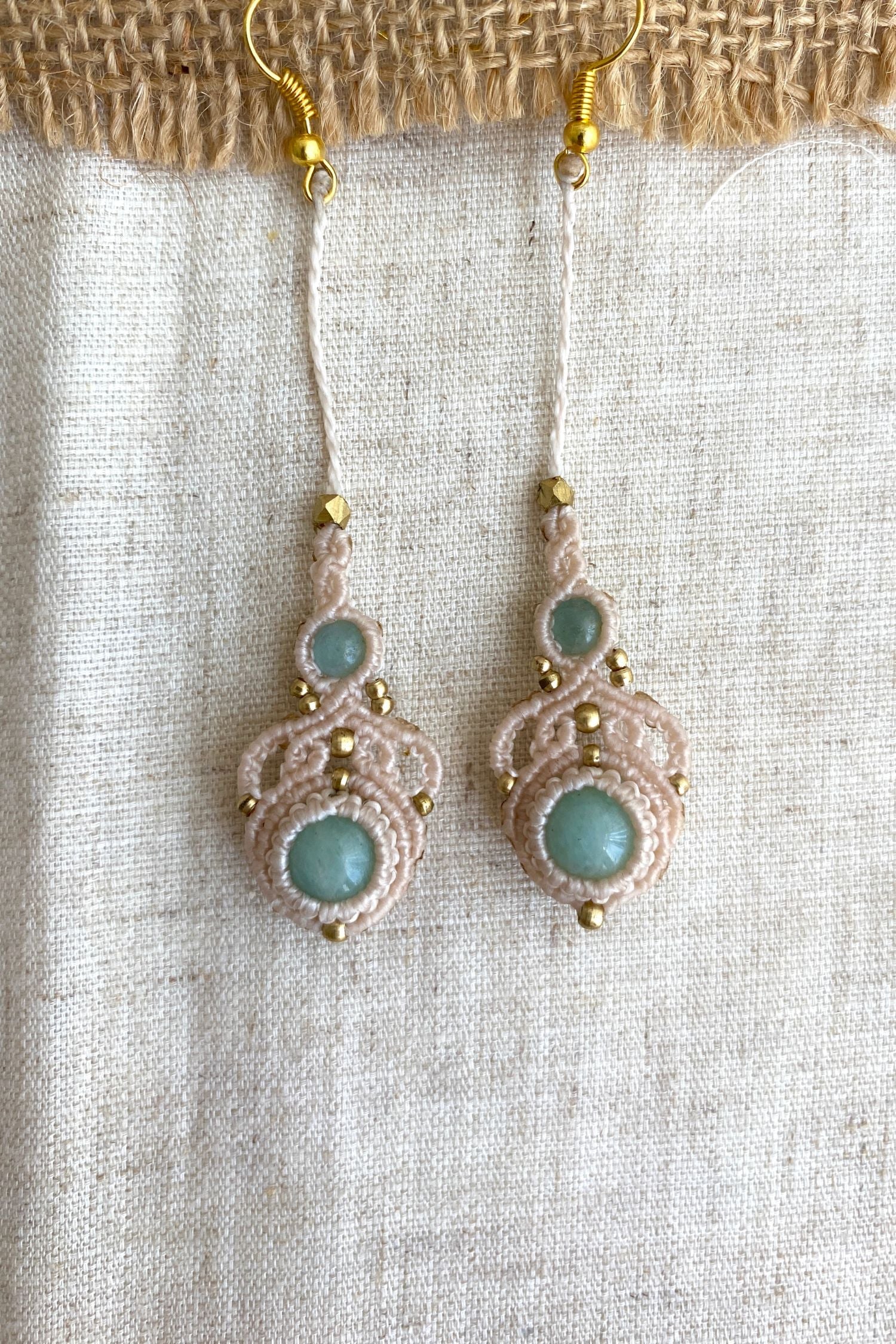 Close-up view of handmade macrame earrings with amazonite and aquamarine gemstones, highlighting the intricate knotting and elegant design.