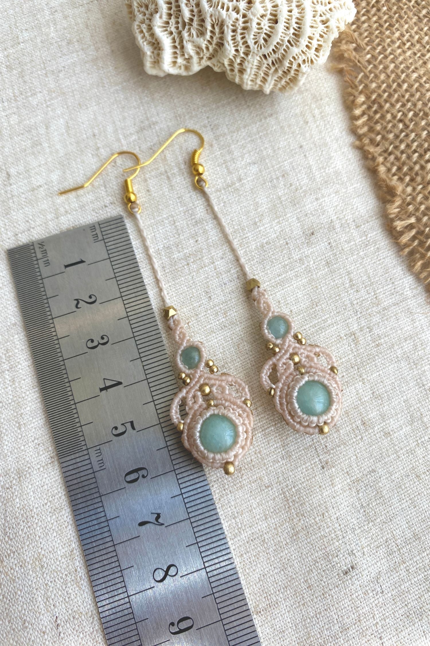 Handmade macrame earrings with amazonite and aquamarine gemstones, laid flat alongside a ruler to show the length and size of the earrings.