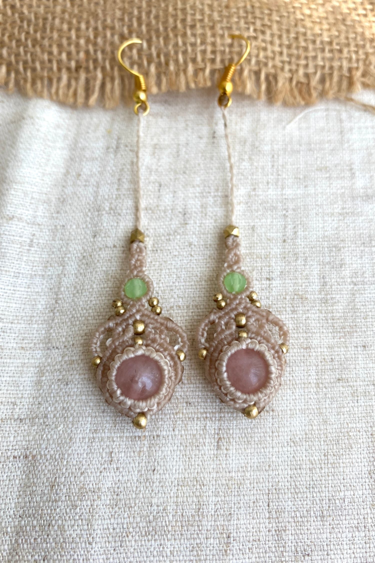 Close-up view of handmade macrame earrings with rose quartz and prehnite gemstones, highlighting the intricate knotting and elegant design.
