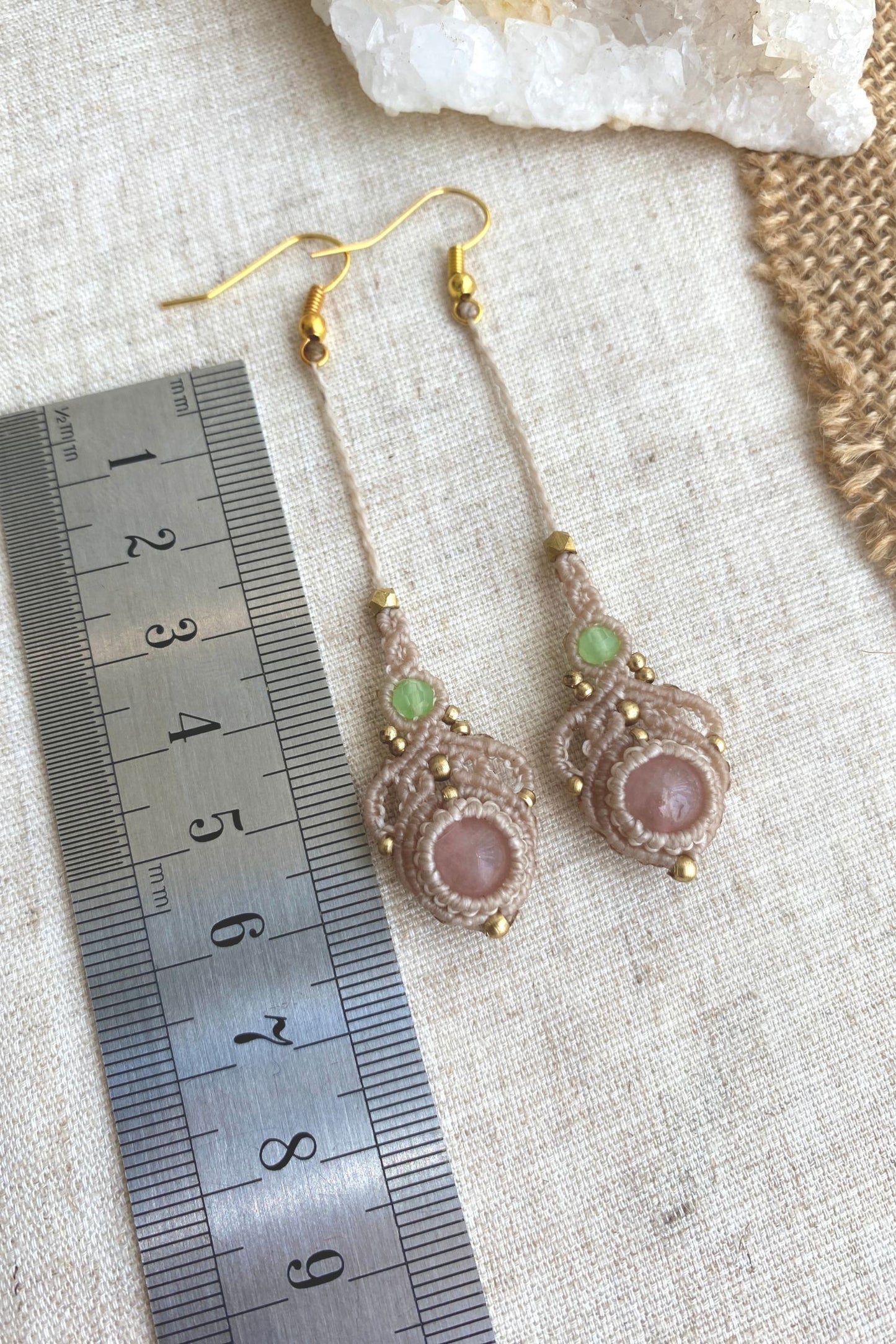 Handmade macrame earrings with rose quartz and prehnite gemstones, laid flat alongside a ruler to show the length and size of the earrings.
