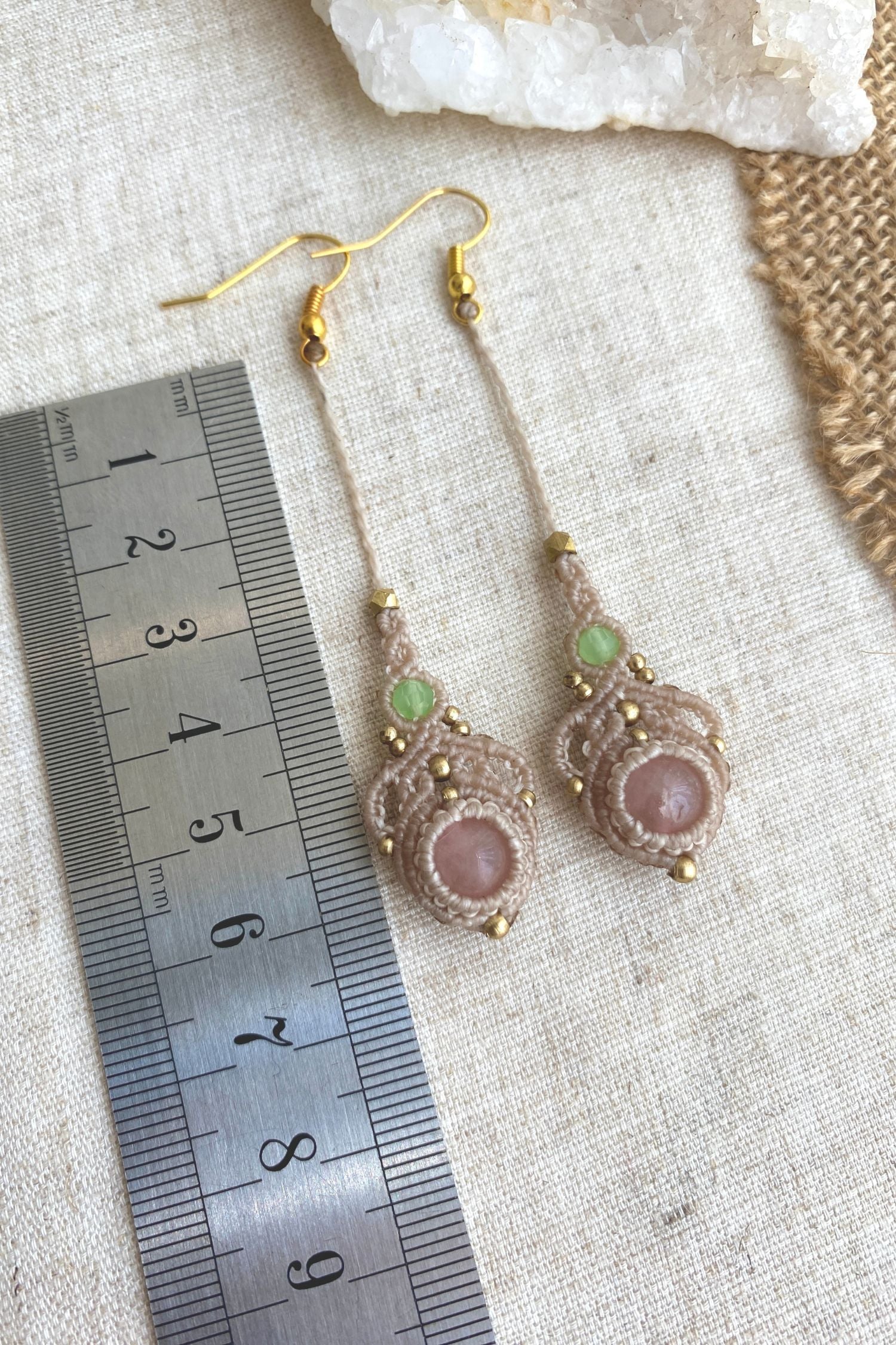 Handmade macrame earrings with rose quartz and prehnite gemstones, laid flat alongside a ruler to show the length and size of the earrings.