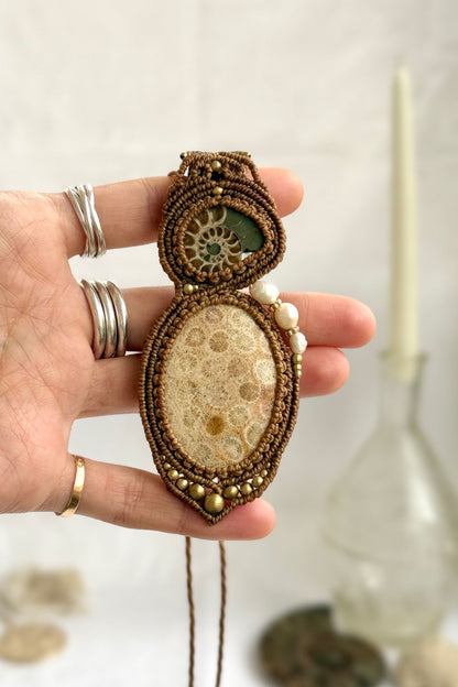 Sliced ammonite and fossil coral statement necklace shown in hand, unique ocean fossil jewelry.