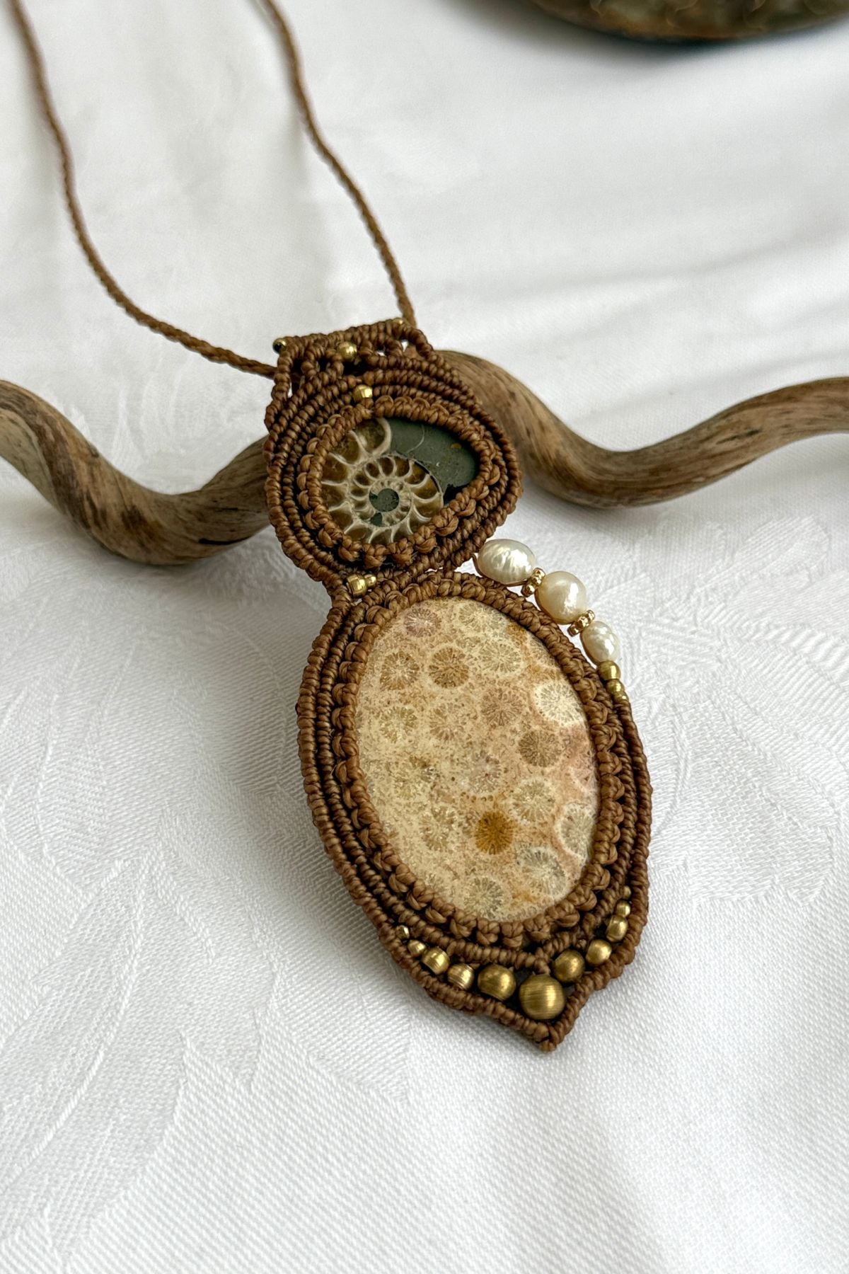 Close-up of rare sliced ammonite and fossil coral pendant with freshwater pearls, natural history jewelry.