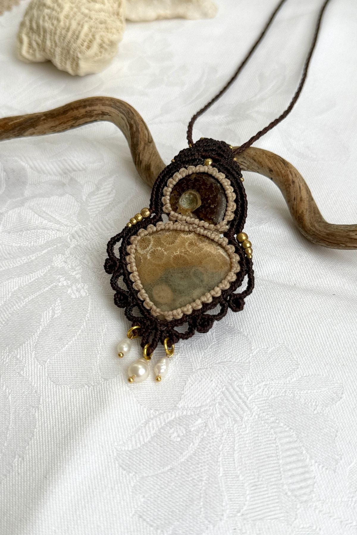 Detailed view of ammonite and coral fossil necklace with organic textures and spiral macrame design