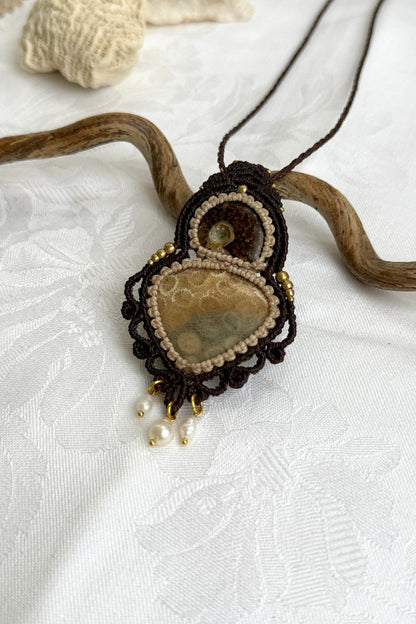 Detailed view of ammonite and coral fossil necklace with organic textures and spiral macrame design