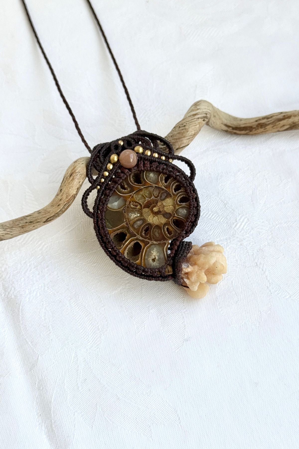 Close-up side view of ammonite fossil pendant necklace highlighting calcite coraloid tentacles