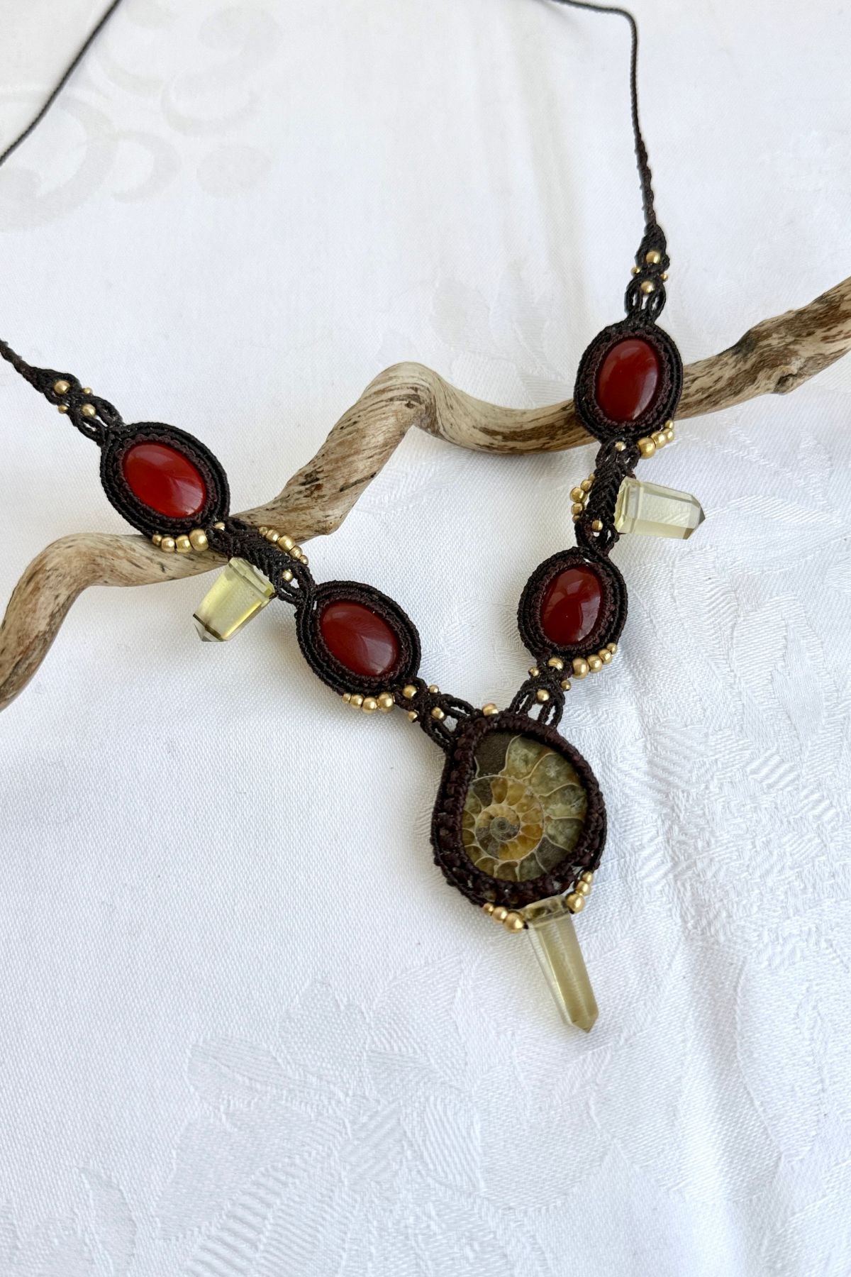 Close-up of V-shaped ammonite necklace side showing carnelian stones and smoky quartz point with detailed macramé work