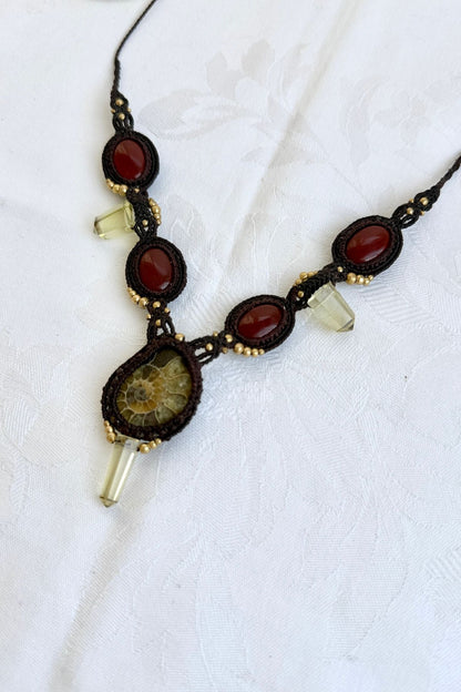 Close-up of opposite side of V-shaped ammonite necklace highlighting vivid carnelian stones and subtle glow of smoky quartz