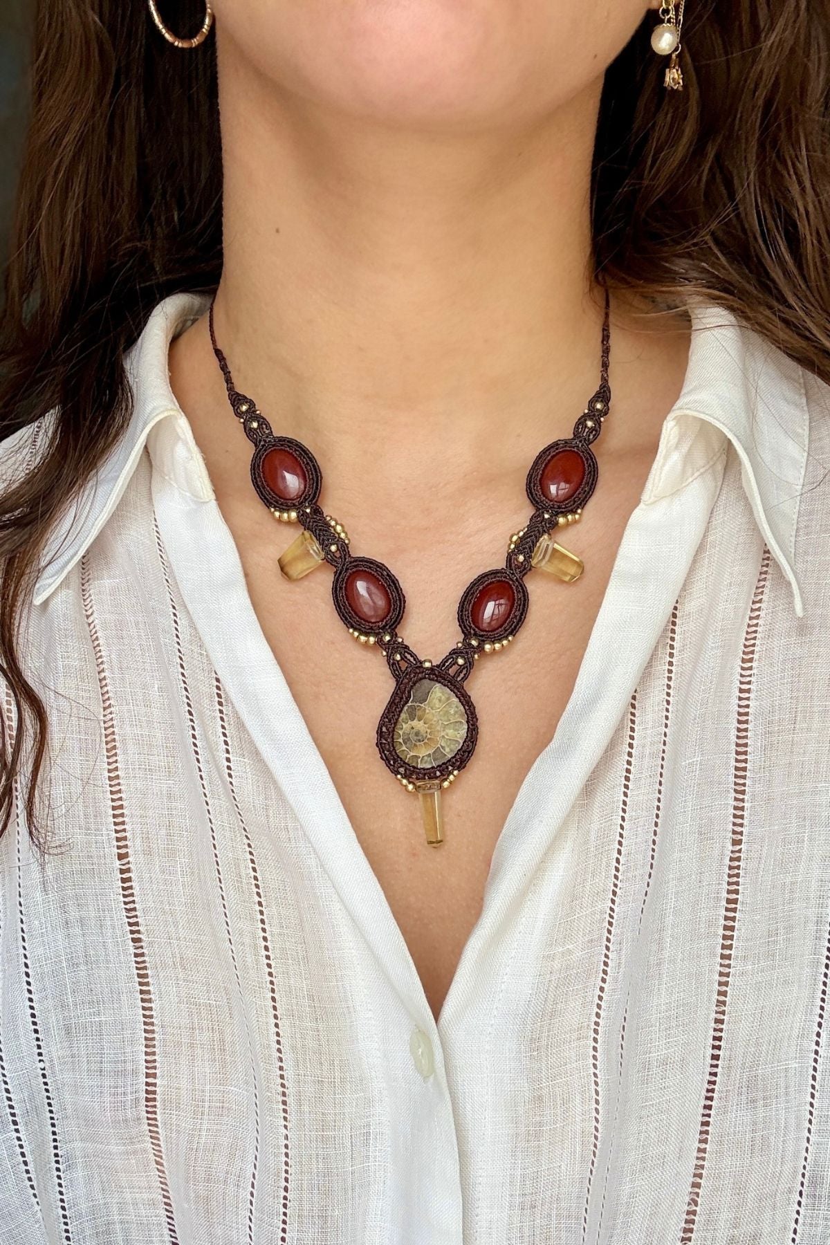 Model wearing V-shaped ammonite necklace with carnelian stones and smoky quartz, showing elegant and bold ocean inspired statement design
