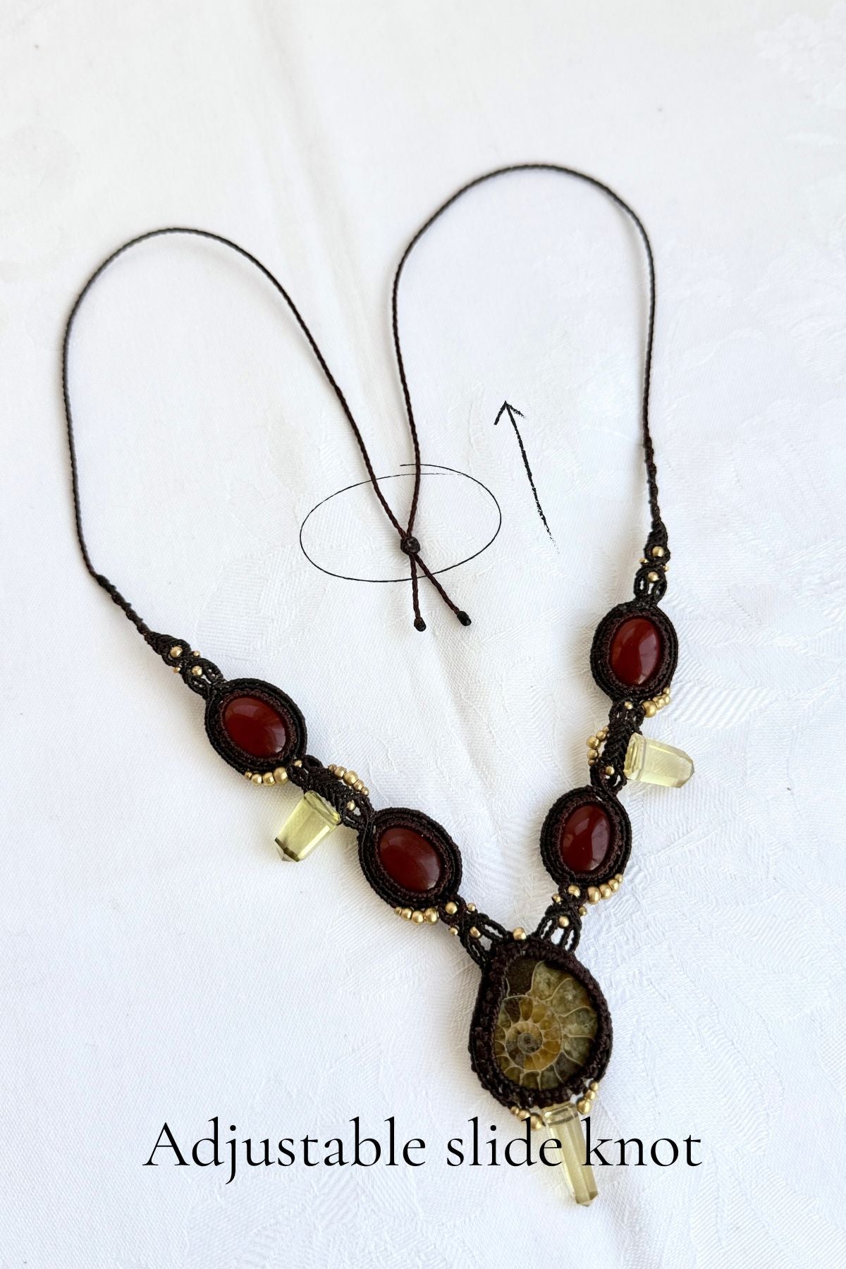 Detail of adjustable slide knots on V-shaped ammonite necklace, allowing versatile fit and maintaining macramé structure
