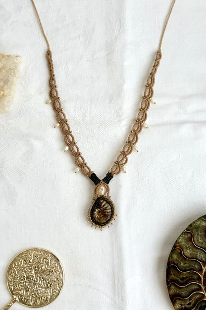 Iridescent ammonite necklace with intricate design and pearl accents extending toward the neckline