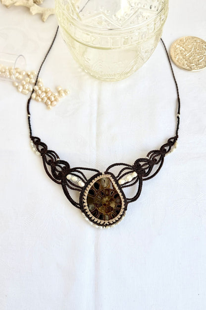 Large ammonite fossil statement necklace with freshwater pearls and coral accents displayed in an ocean inspired styled scene