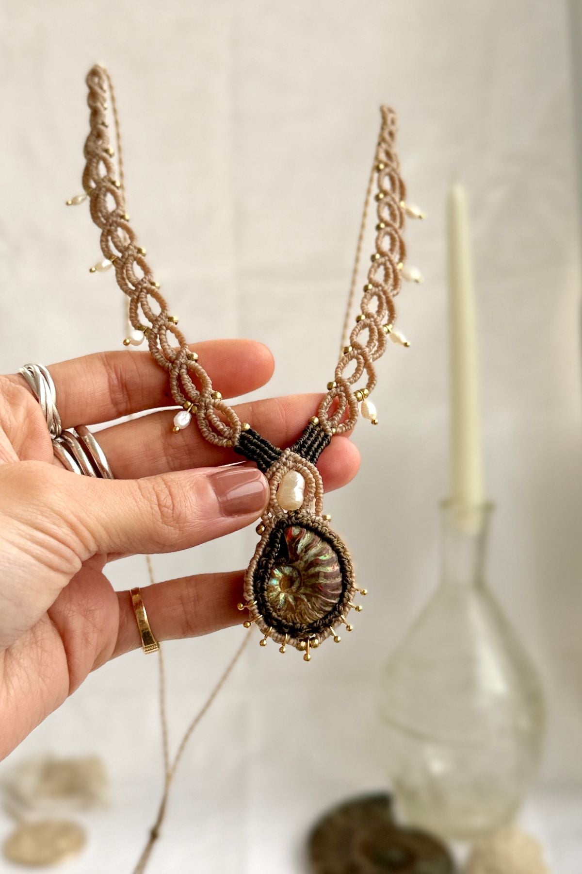 Iridescent ammonite and pearl statement necklace shown in hand, unique fossil jewelry