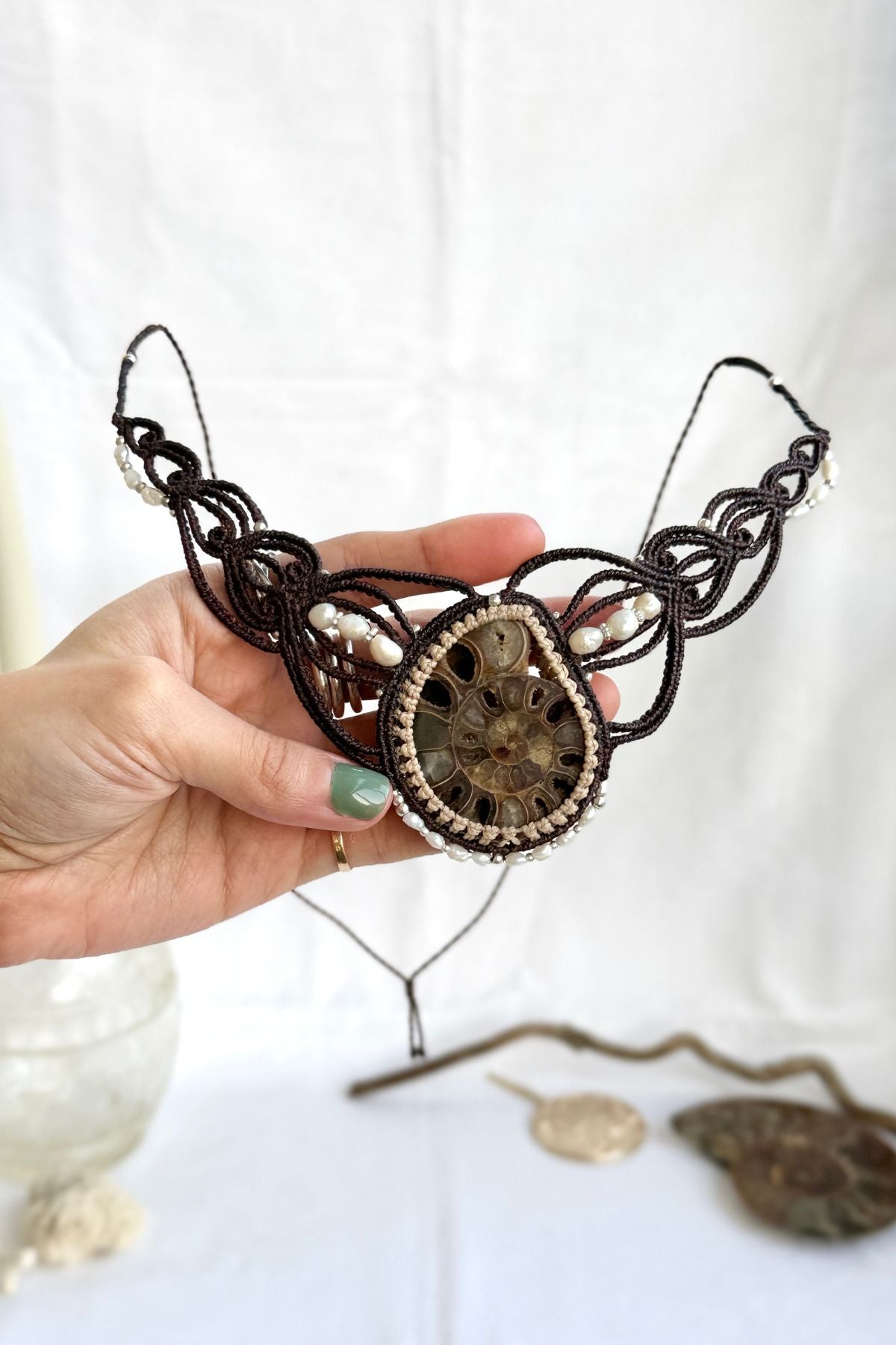 Hand holding one of a kind ammonite fossil statement necklace showing size, pearl details, and natural crystal-lined cavities