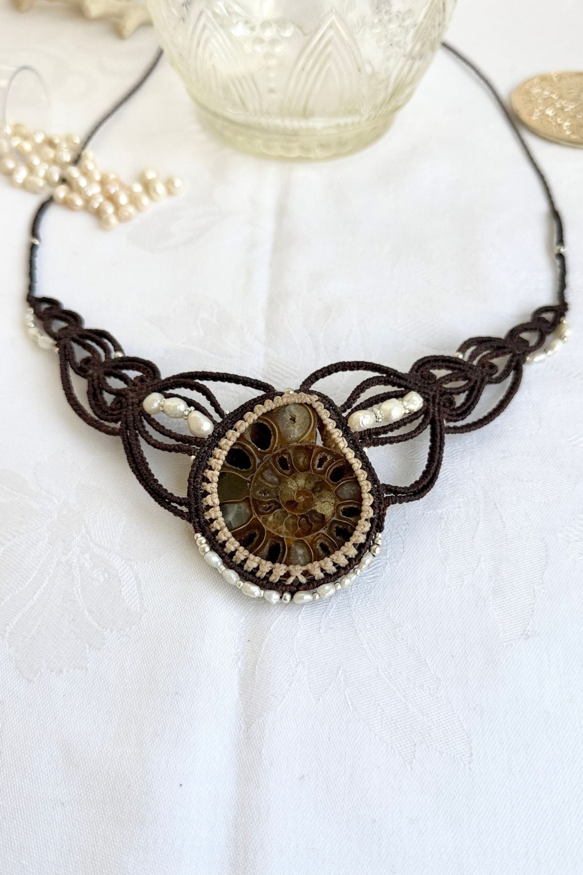 Close-up front view of ammonite fossil necklace with natural crystal-lined chambers and surrounding freshwater pearls