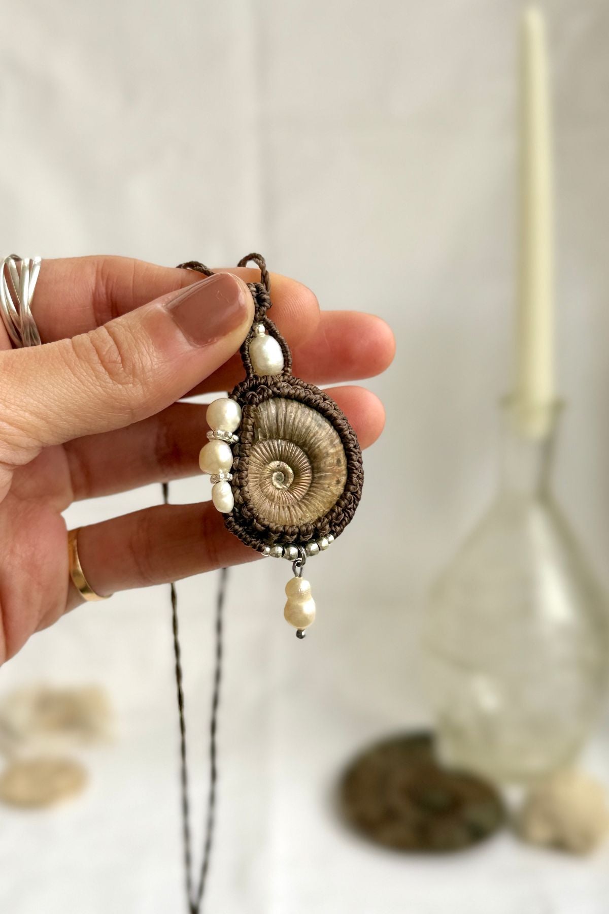 Raw ammonite fossil statement necklace shown in hand, unique ocean jewelry