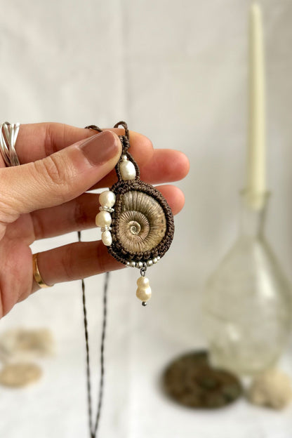 Raw ammonite fossil statement necklace shown in hand, unique ocean jewelry