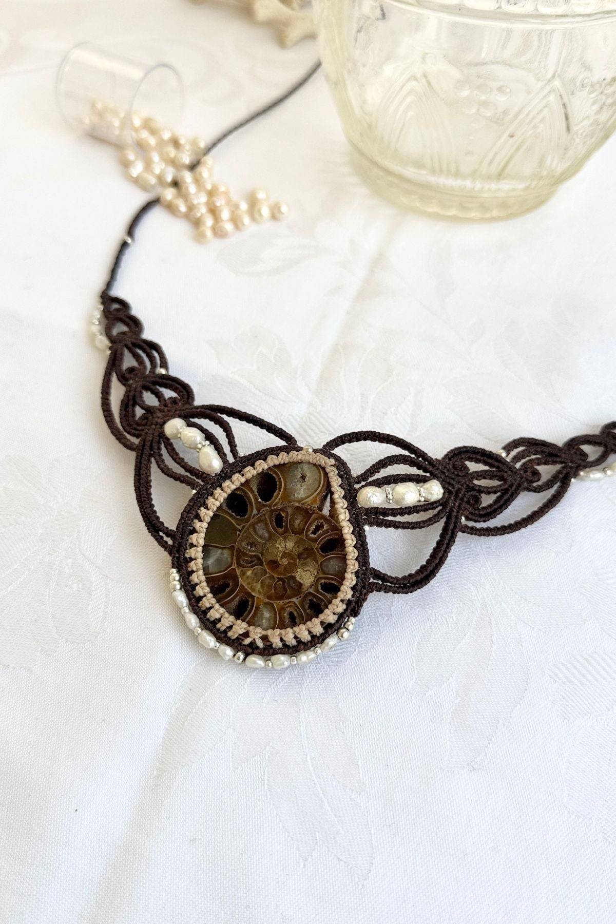 Side view close-up of V-shaped ammonite fossil statement necklace highlighting pearl placement and organic asymmetry