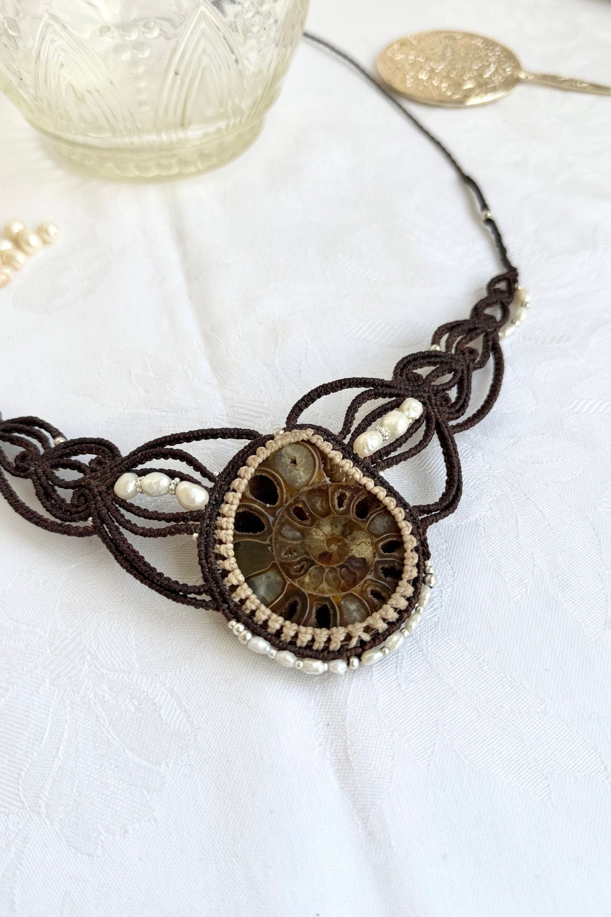 Close-up of right side of large ammonite fossil necklace showing crystal details, pearls, and artisanal macramé craftsmanship