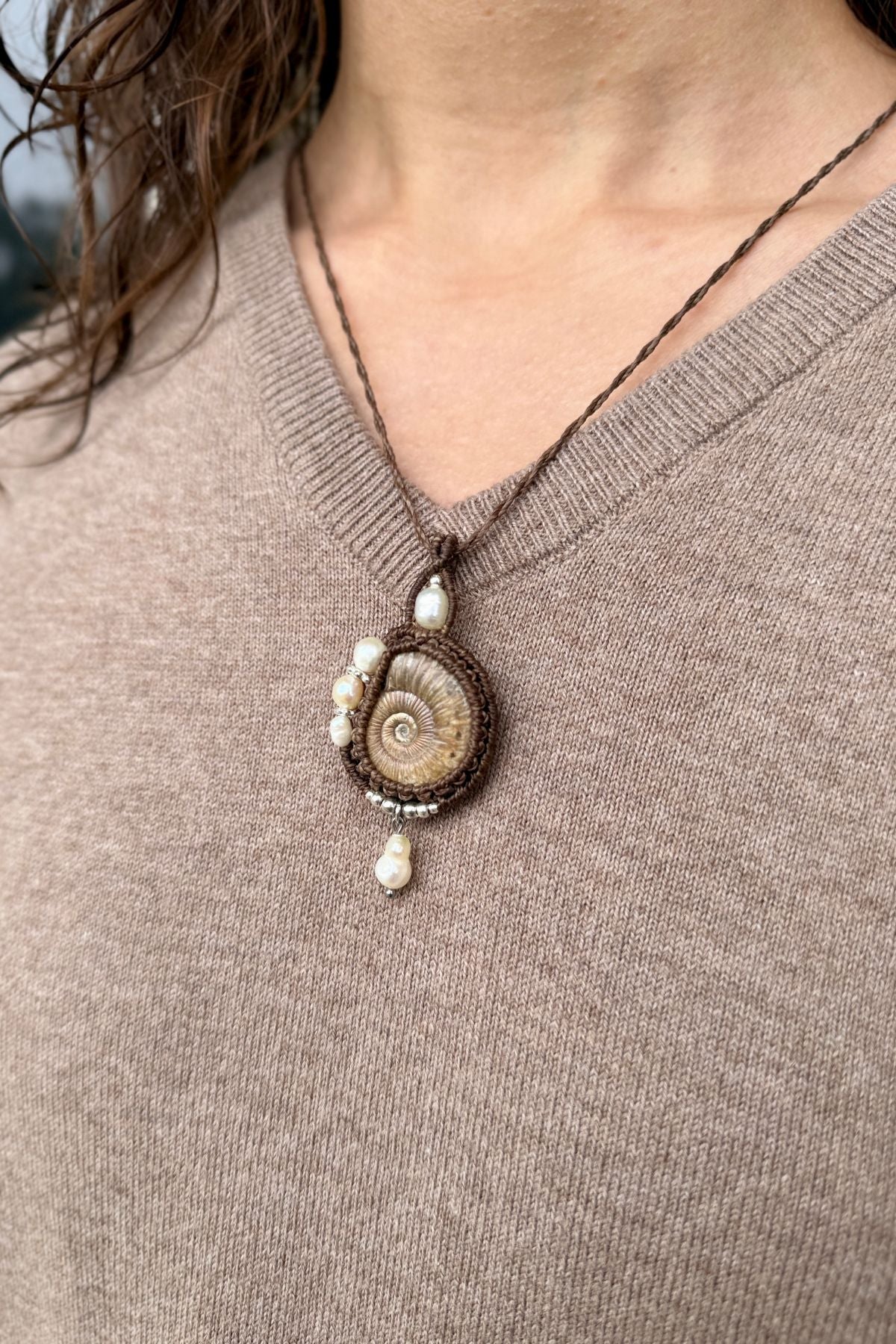 Model wearing ammonite fossil necklace with elegant freshwater pearls design