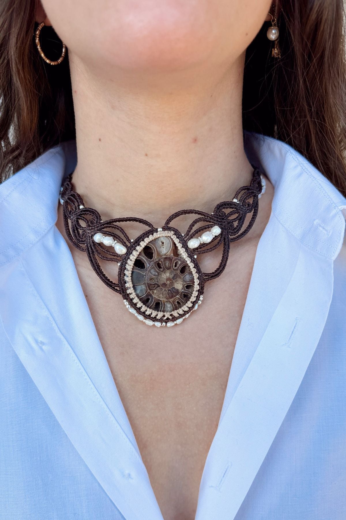 Model wearing large ammonite fossil statement necklace with freshwater pearls in V-shaped design, ocean inspired one of a kind jewelry