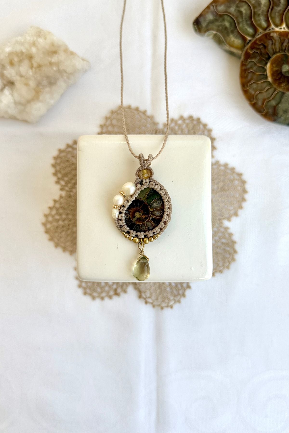 Ammonite fossil necklace with pearls and lemon quartz drop laid flat in ocean inspired setting