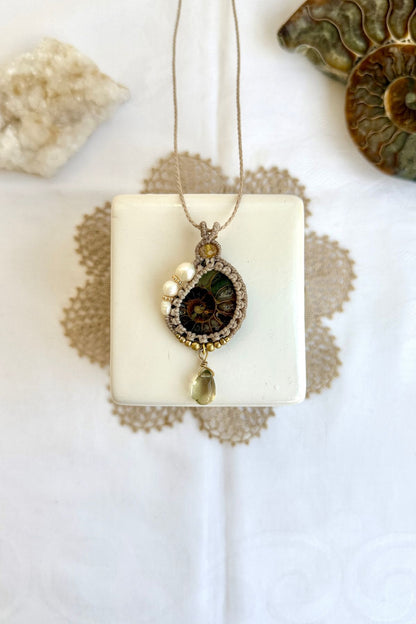 Ammonite fossil necklace with pearls and lemon quartz drop laid flat in ocean inspired setting