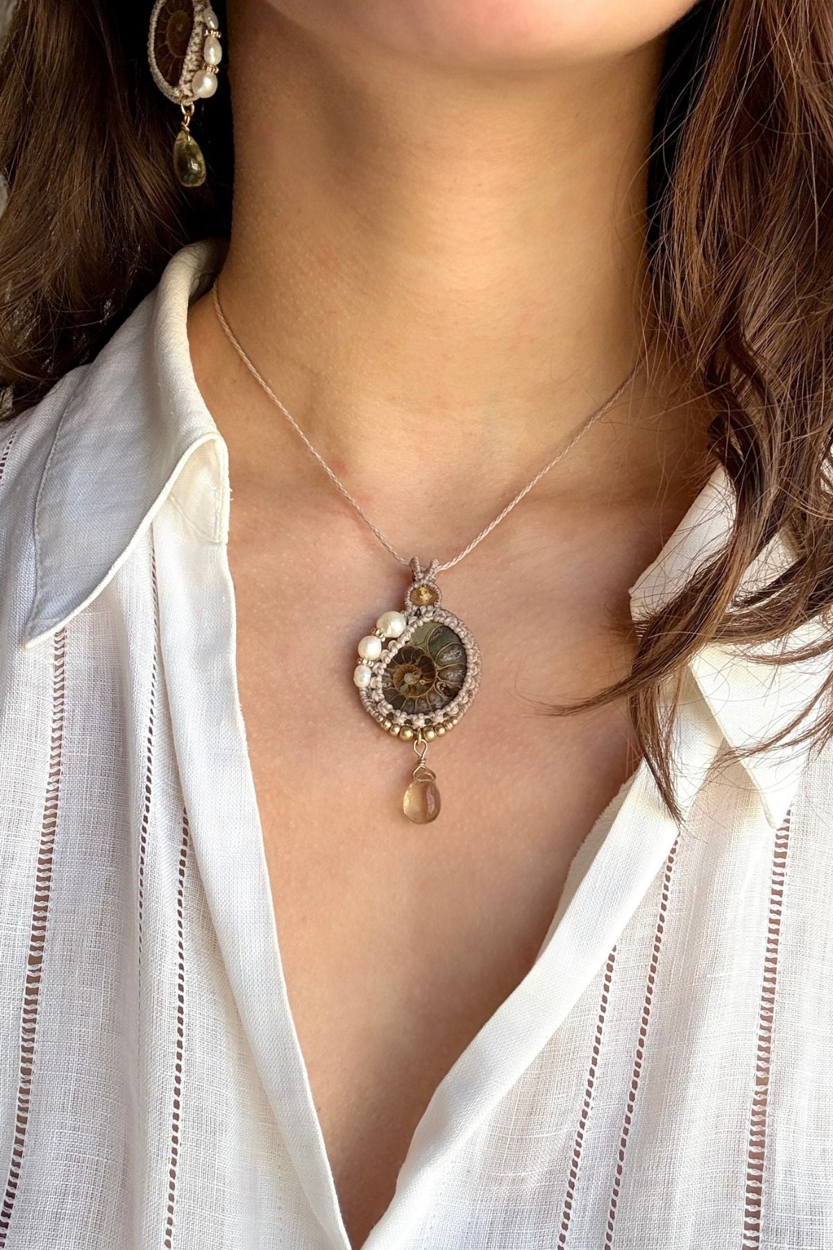 Model wearing ammonite fossil necklace with freshwater pearls and lemon quartz drop, ocean inspired statement jewelry