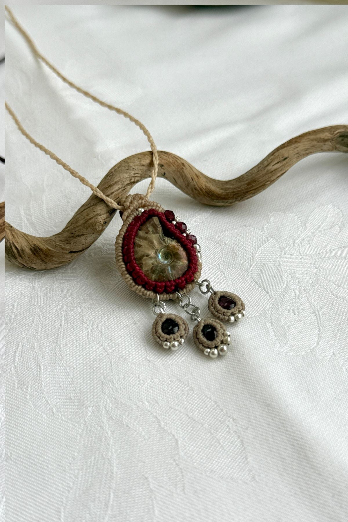 Close-up of iridescent ammonite surface with deep red garnet drop details