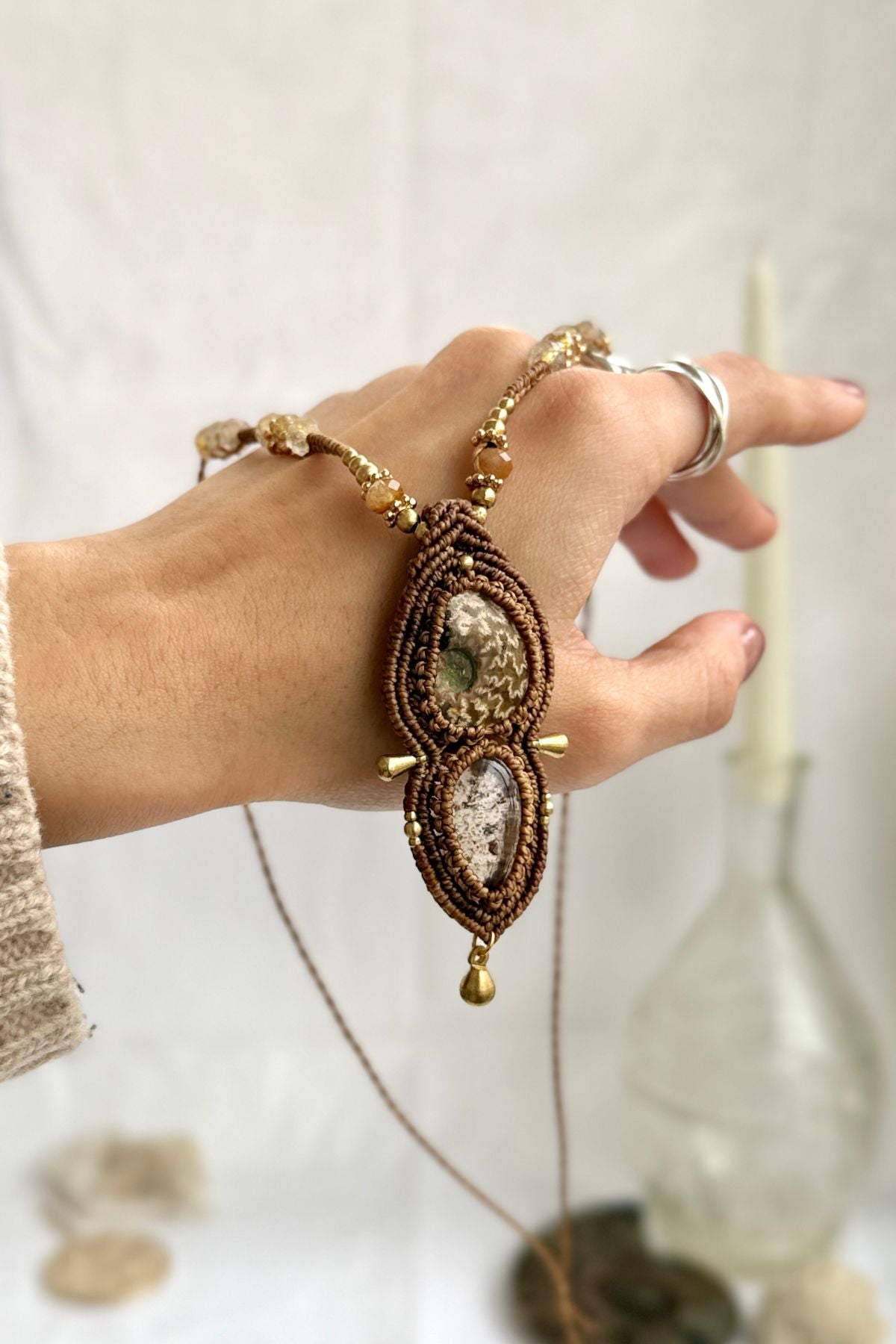 Rare patterned ammonite and lodolite necklace shown over hand, with faceted rutilated quartz beads