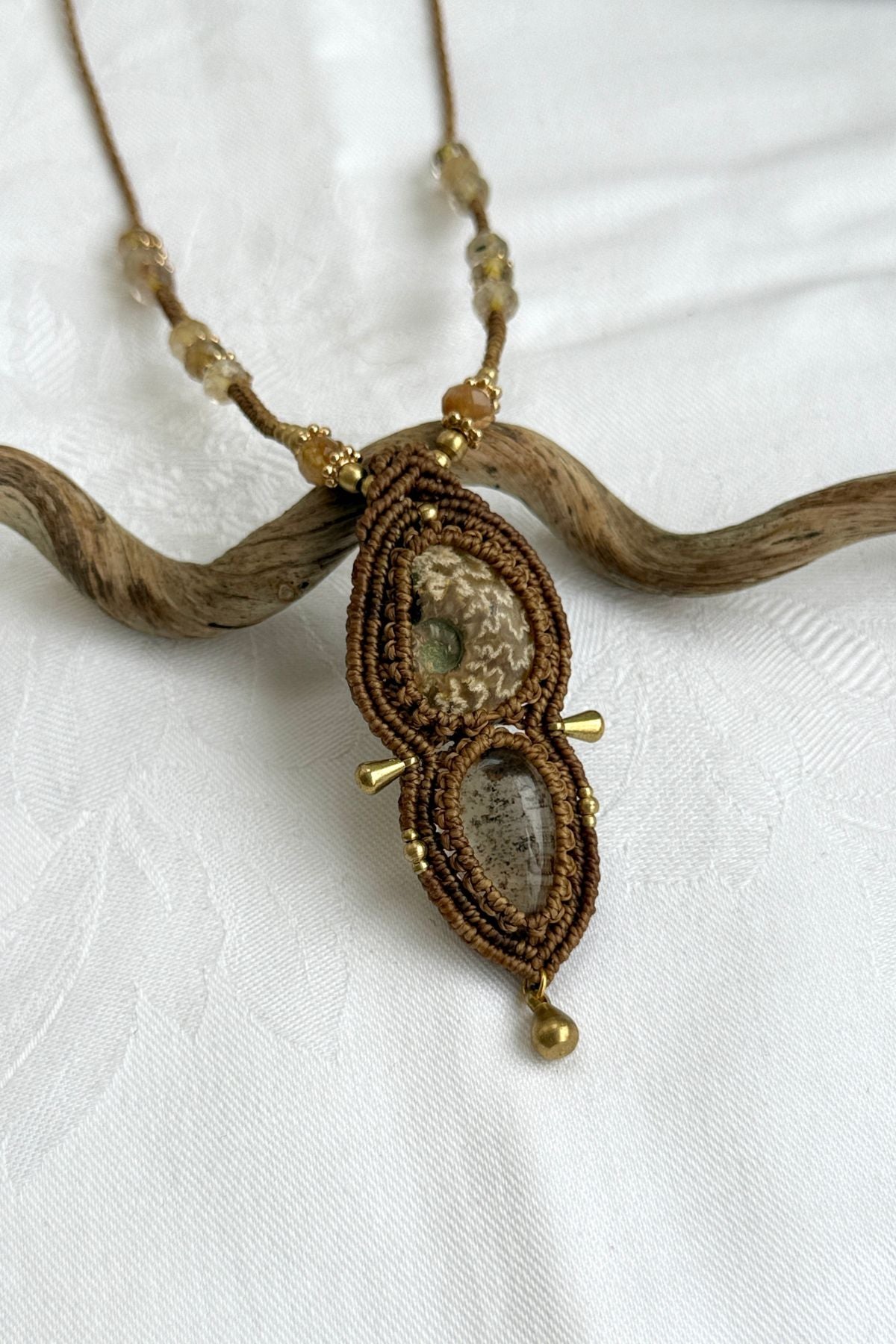 Close-up of ammonite fossil with natural pale veining and lodolite gemstone, showing rutilated quartz detail