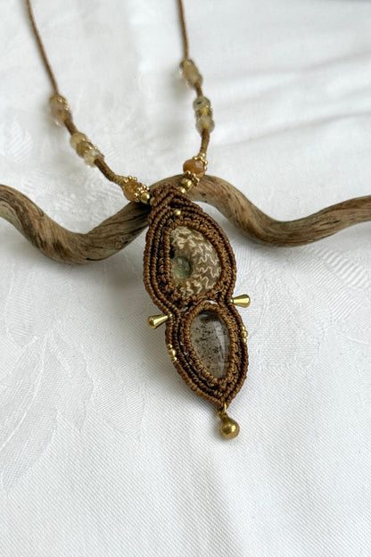 Close-up of ammonite fossil with natural pale veining and lodolite gemstone, showing rutilated quartz detail