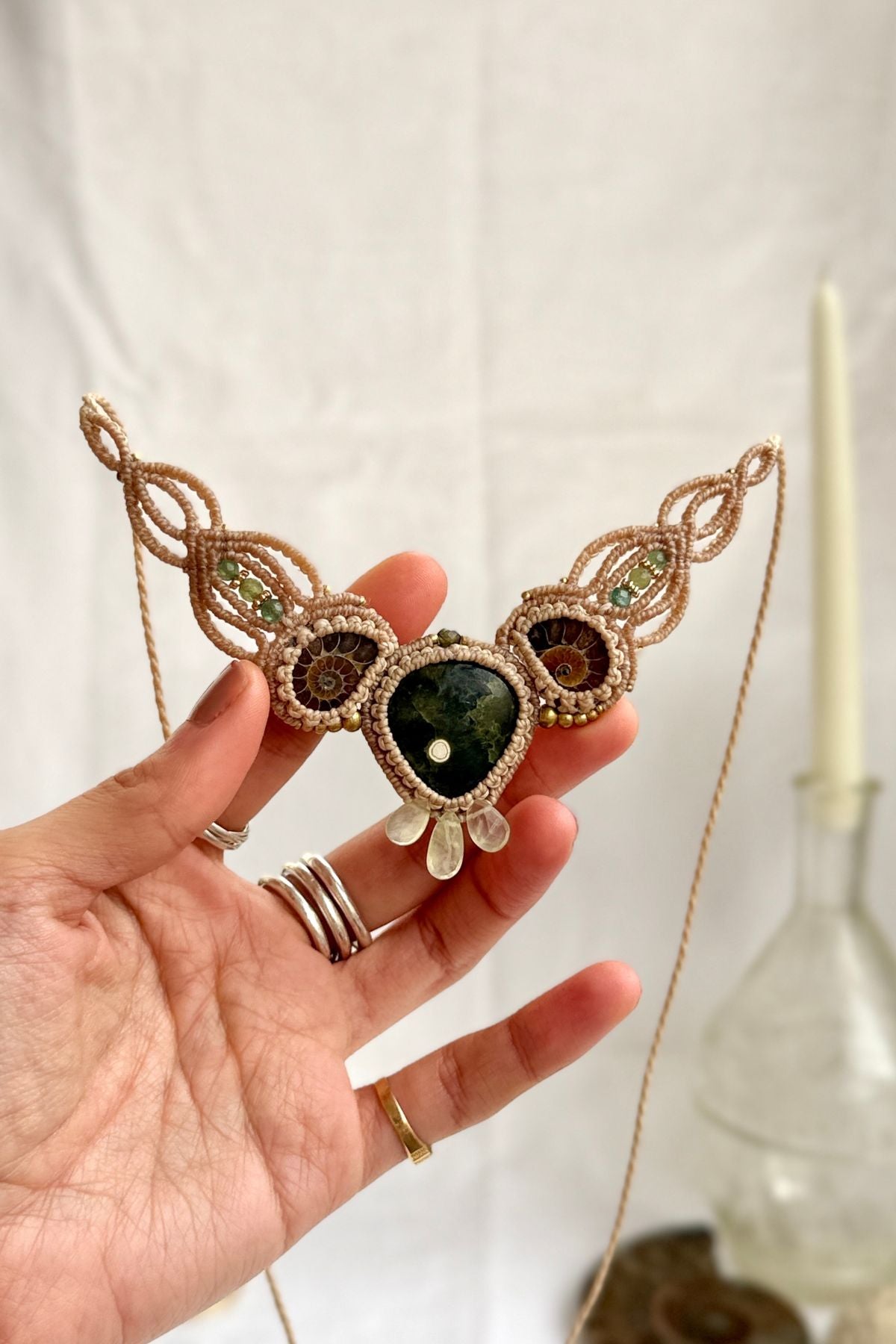 Rare ocean jasper necklace with split ammonite and green tourmaline, shown in hand, elegant fossil jewelry
