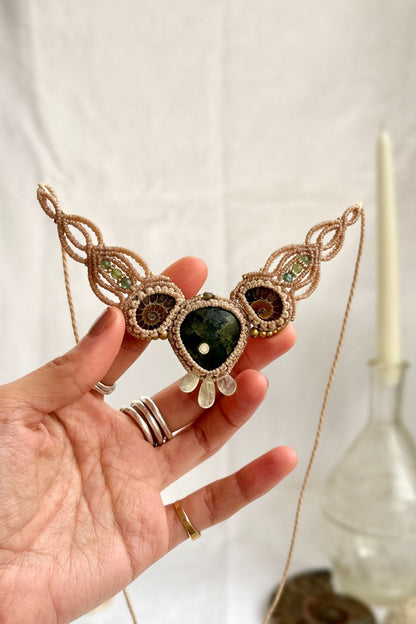 Rare ocean jasper necklace with split ammonite and green tourmaline, shown in hand, elegant fossil jewelry