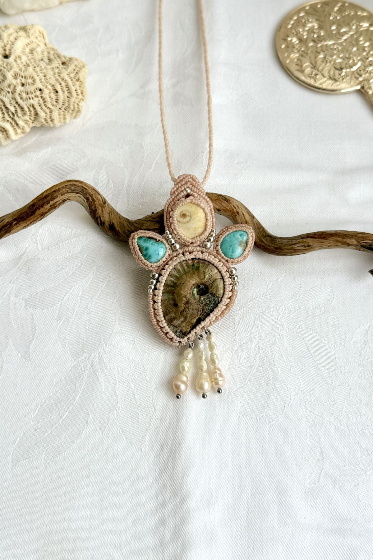 Detailed top view of iridescent ammonite with ocean blue larimar and pearl accents