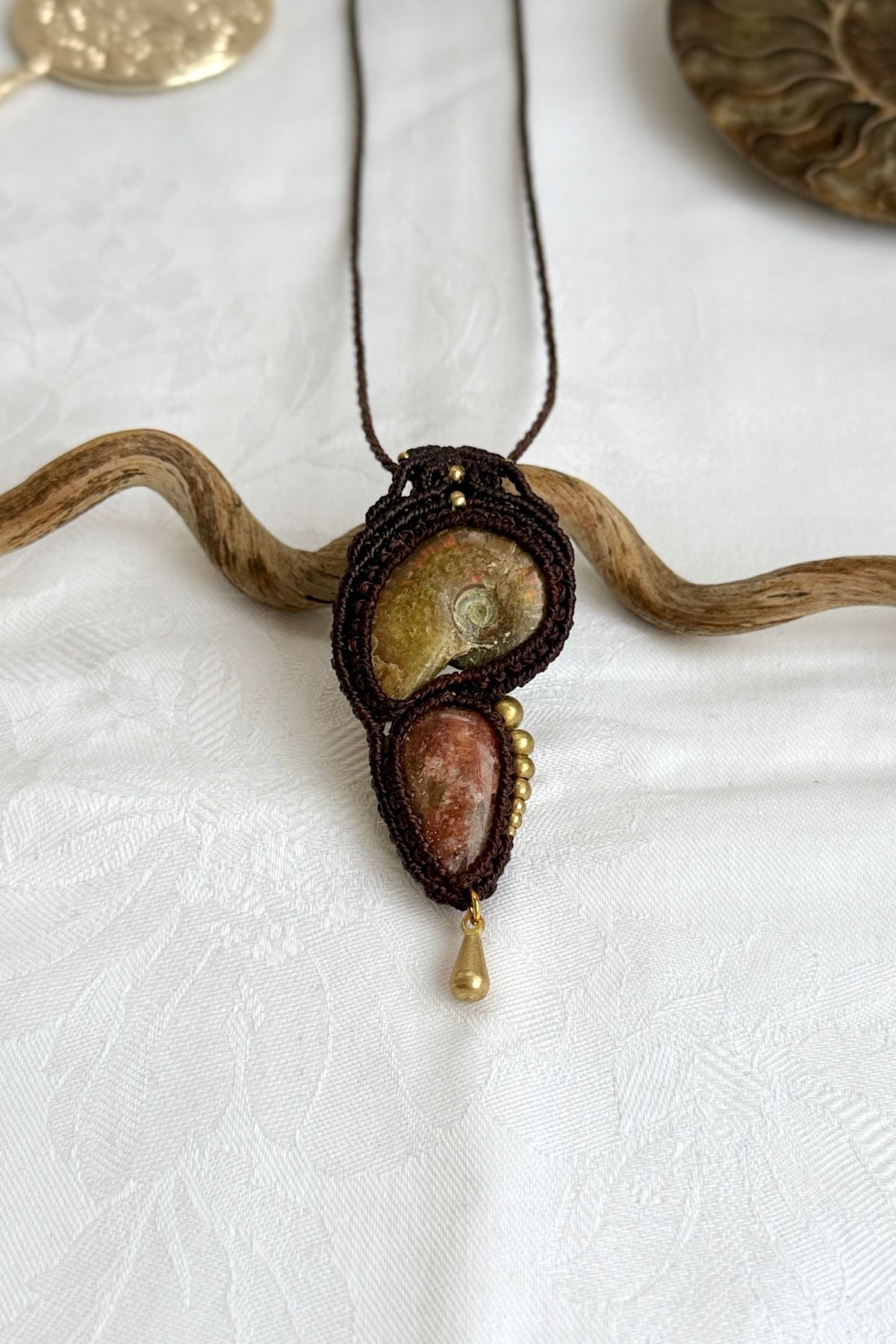 Detailed top view of ammonite with red and green iridescent tones, sunstone glow, and asymmetric bead arrangement