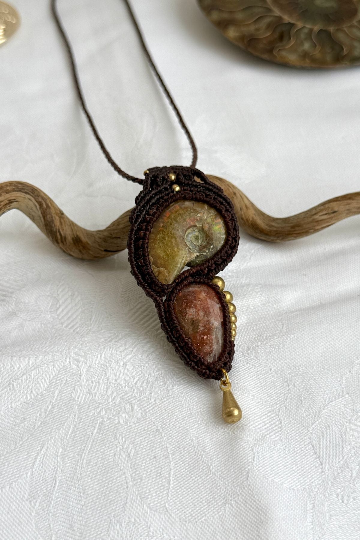 Detailed view of asymmetric bead pattern, opalized ammonite, and sparkling sunstone in one of a kind pendant