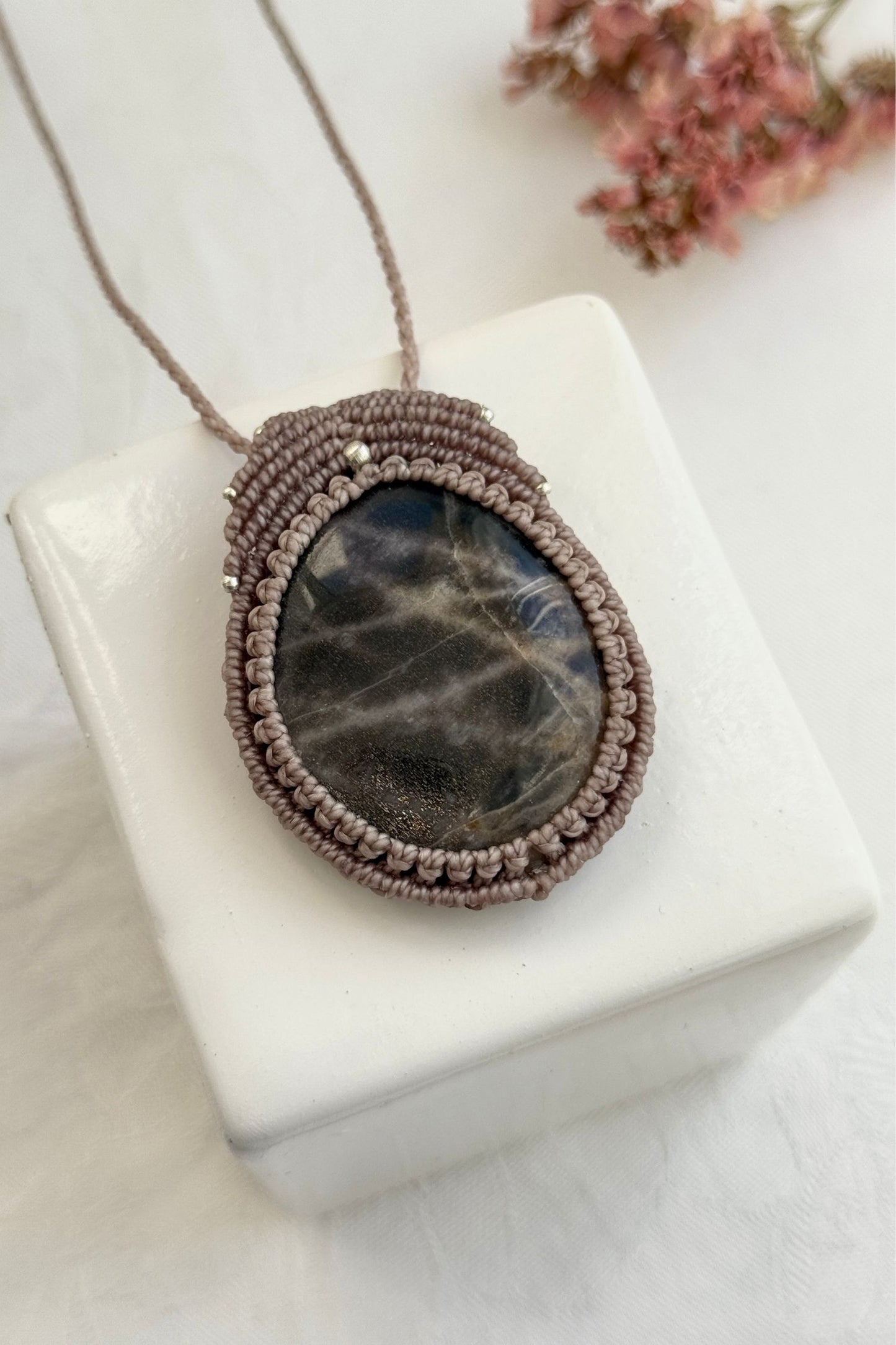 Detailed close-up of Black Moonstone gemstone in a handmade macrame necklace. Showcasing natural textures and gemstone glow.