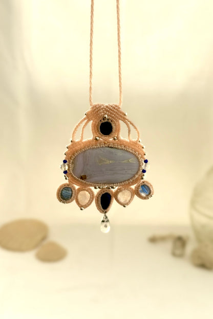 Hanging view of a gemstone macrame necklace showing the transparency and natural textures of Blue Lace Agate, Quartz, and Moonstone