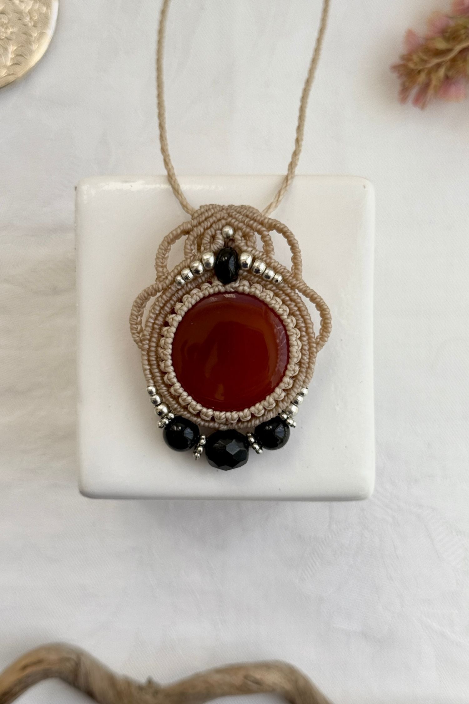 Handmade macrame necklace with Carnelian and Onyx gemstones, part of the Nocturnal Collection. One-of-a-kind design, laid flat for an artistic display.