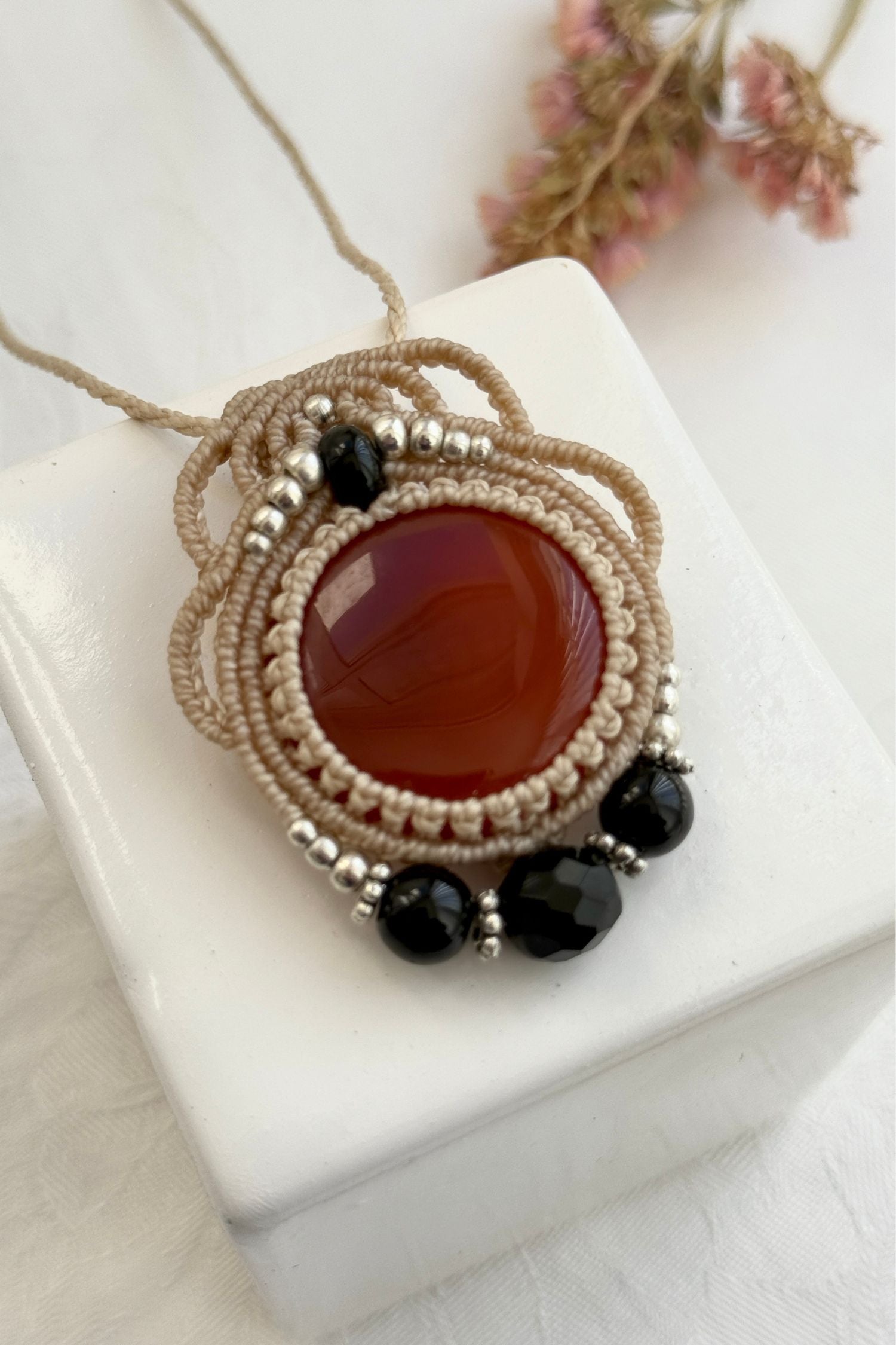 Detailed close-up of Carnelian and Onyx gemstones in a handmade macrame necklace. Showcasing natural textures and gemstone glow.