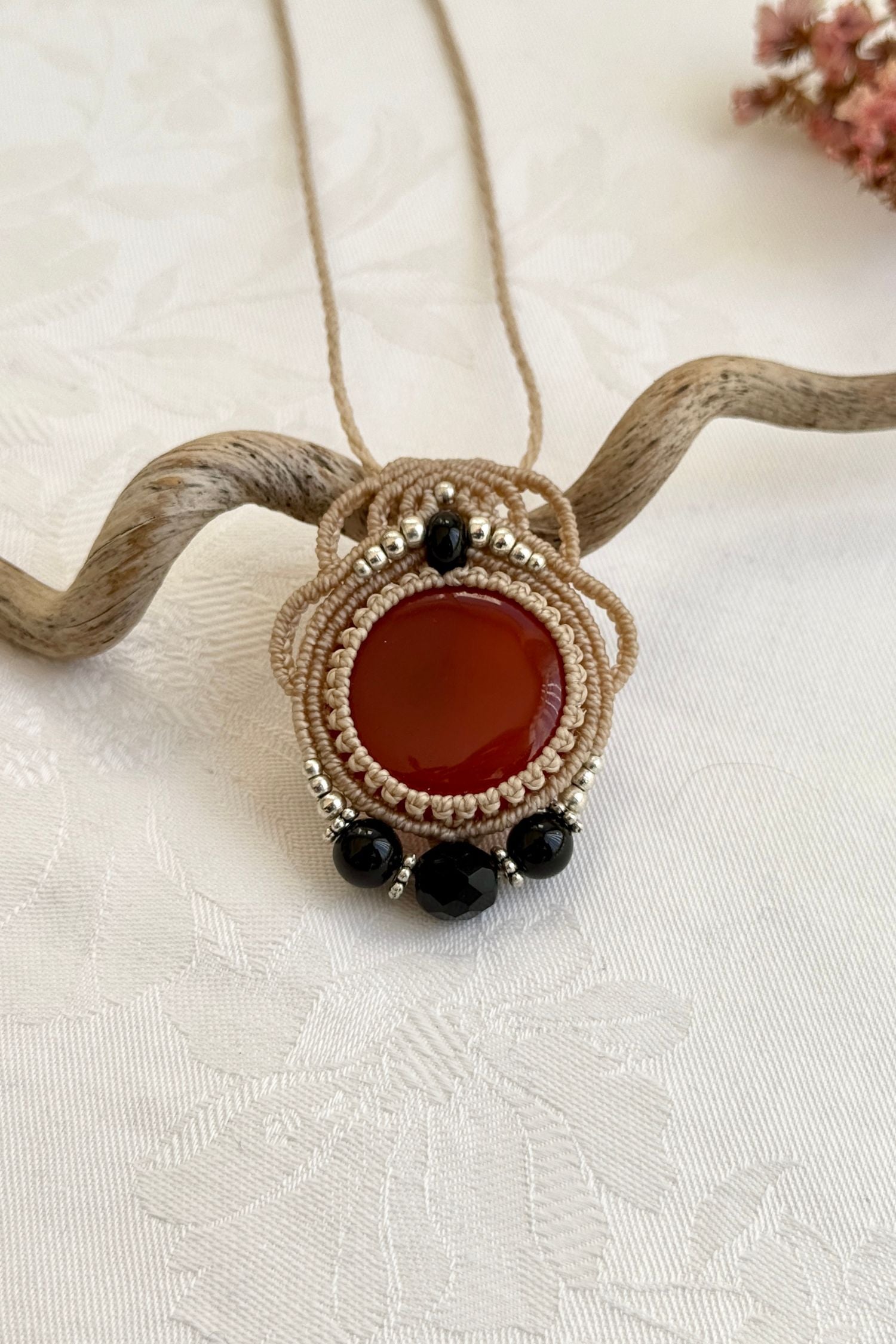  Close-up of the Carnelian and Onyx macrame necklace in a unique setting. Highlighting the craftsmanship and gemstone details.
