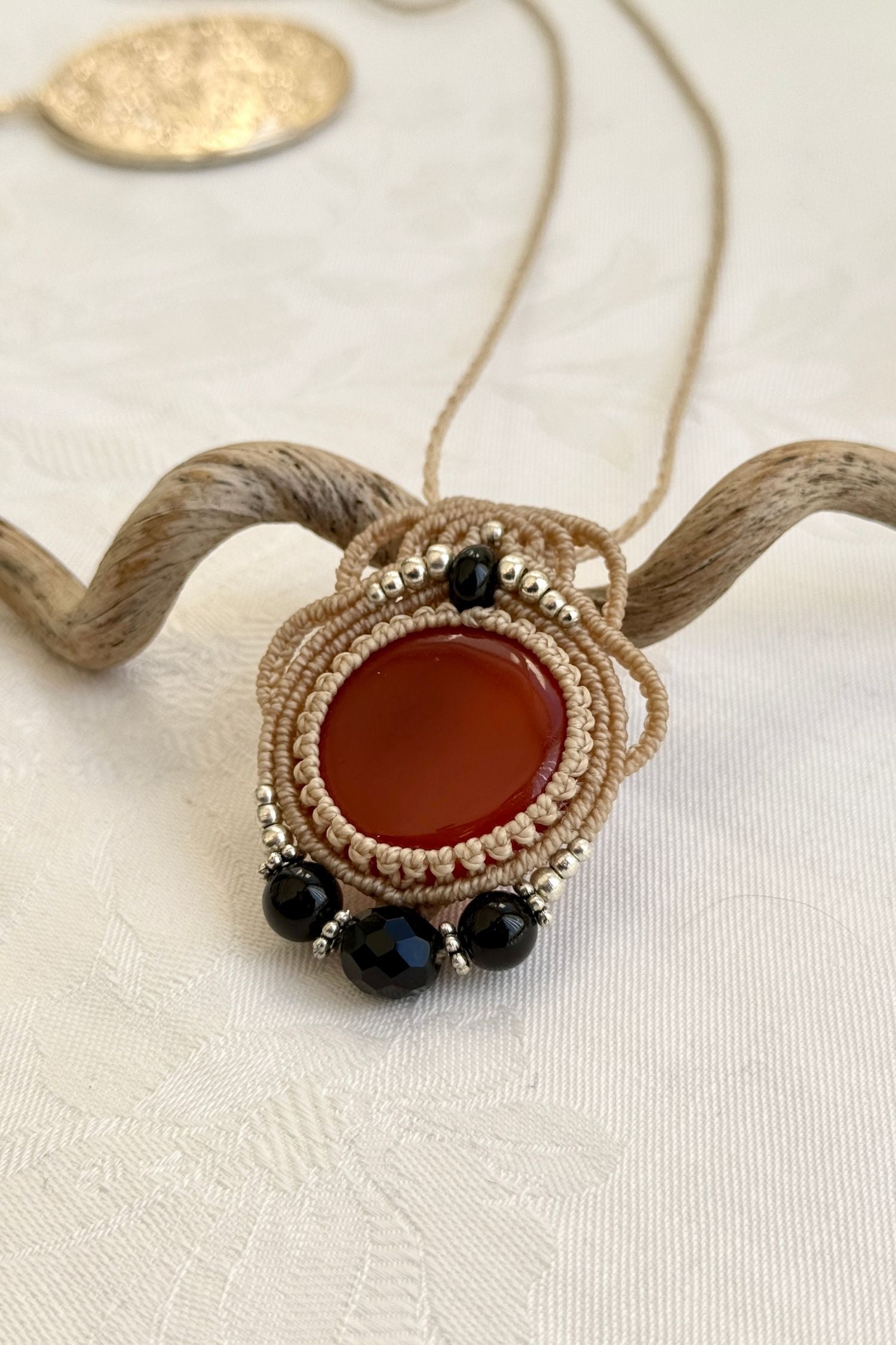Side-angle view of the handmade macrame necklace with Carnelian and Onyx. Showcasing depth, knotting details, and stone textures.