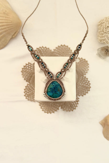 Handmade Chrysocolla macramé necklace laid in a styled setting, highlighting its V-shaped design and earthy blue tones