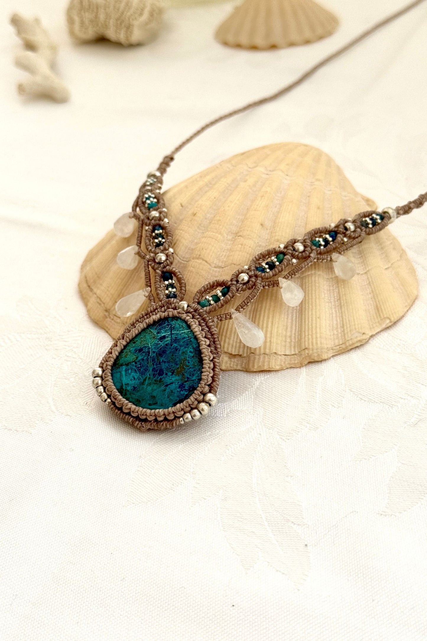 Side view of a handmade Chrysocolla macramé necklace showing layered design and beige cord texture