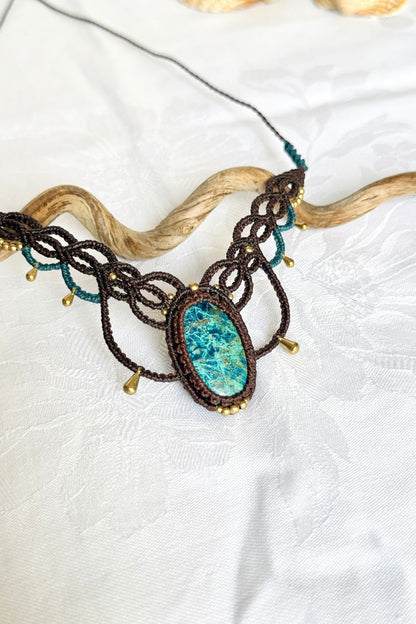 Close-up of the oval chrysocolla stone showing blue-green tones and intricate pale veining, framed by brown macrame.