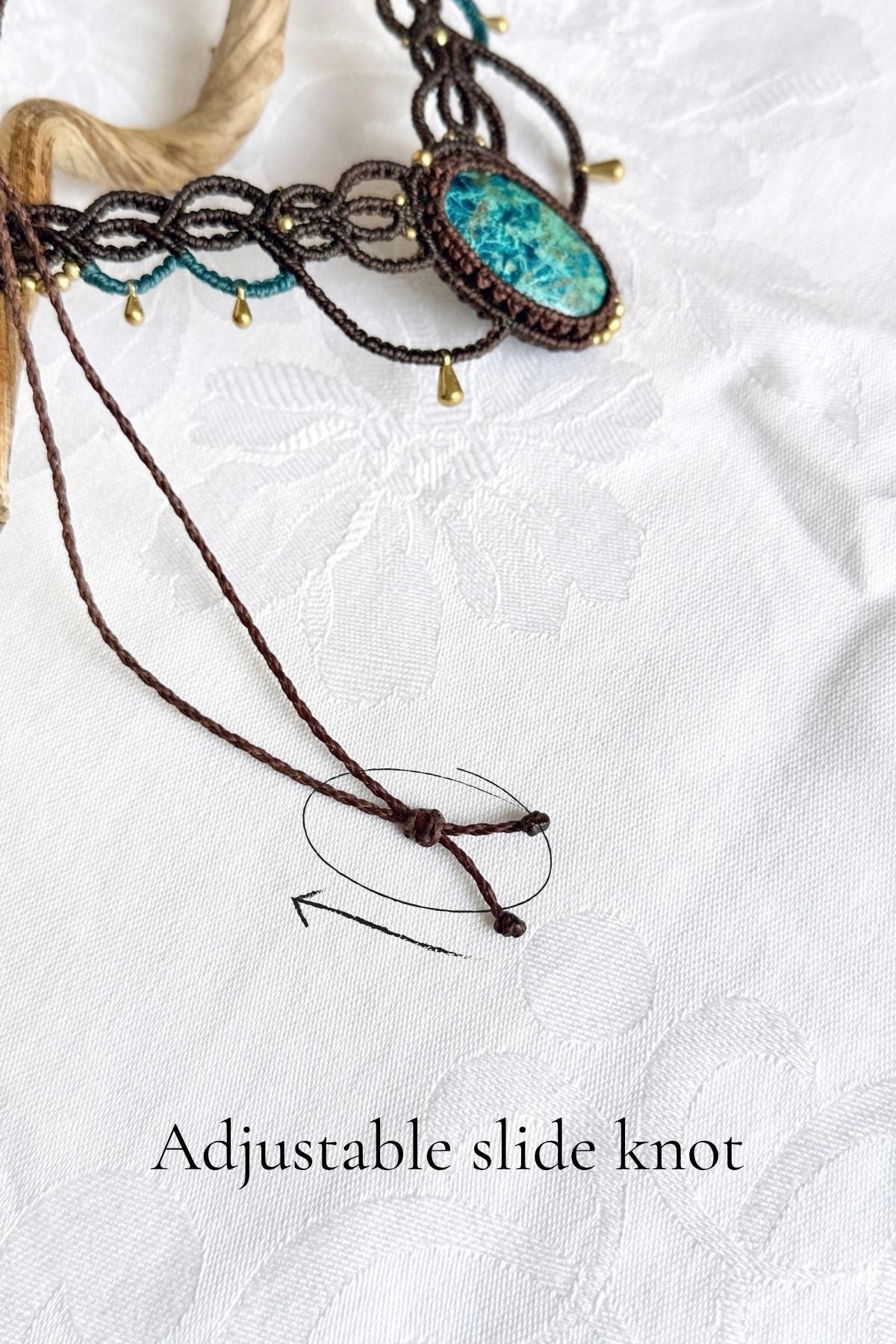 Close-up of the necklace’s brown cord sliding knot, with an arrow and text showing how to adjust the length.
