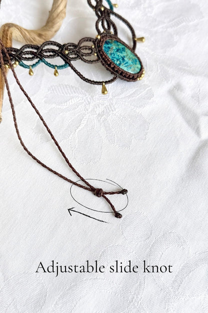 Close-up of the necklace’s brown cord sliding knot, with an arrow and text showing how to adjust the length.